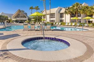 奥兰多萨巴尔棕榈万豪酒店的度假村旁的圆形游泳池配有椅子和遮阳伞