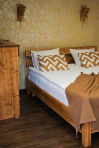 斯捷潘纳万EcoLife Lodge Hotel & Restaurant的一间卧室配有一张带白色床单和枕头的木制床。