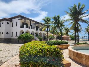 Six HutsBeachfront Condo directly on the private beach - Ground Floor的一座种植了棕榈树和游泳池的大型白色房屋