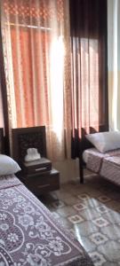 安曼Jawal Hotel的一间卧室设有两张床、窗帘和窗户。