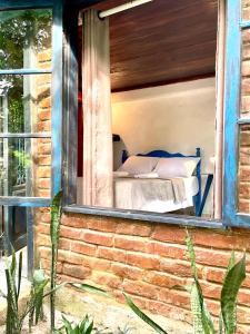 阿布拉奥Casa Selva - Vila do Abraão - Ilha grande的砖房窗户上的一张床位
