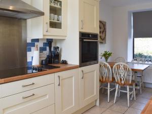 LlandwrogTy Newydd的厨房配有白色橱柜和桌椅