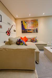 贝洛奥里藏特apartamentos Coração Eucarístico的一间配有沙发的房间和墙上的吉他