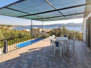 维甘Seaside family friendly house with a swimming pool Viganj, Peljesac - 10253的阳台的天井配有桌椅