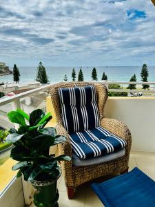 Manly SeaDreams Beachfront Manly的俯瞰大海的阳台上的藤椅