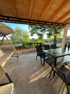 扎达尔Relax and Unwind: Family-Friendly House near Zadar in Zagrad的木制屋顶下带桌椅的天井