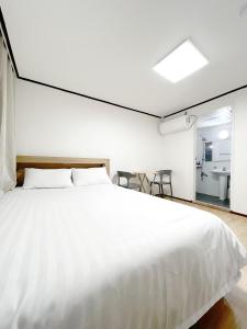 济州市The Oakra Hotel的一间带白色大床的卧室和一间浴室