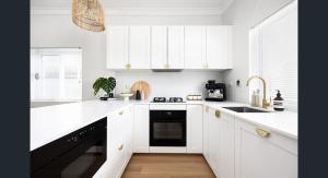 悉尼The South bay's home-Big RoomA的白色的厨房配有白色橱柜和黑色洗碗机