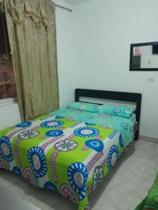 波帕扬HOTEL CASA BLANCA的一间卧室配有一张带绿色和蓝色棉被的床