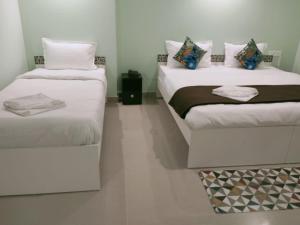 甘托克Hotel BJ的配有白色墙壁的小客房内的两张床