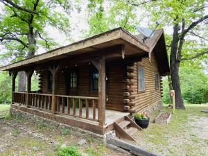 尤里卡斯普林斯Cozy Cabin at Bear Mountain Log Cabins的树林中的小木屋,设有门廊