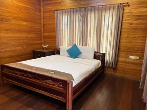 农布Sirilagoona Home Resort的木墙和窗户的客房内的一张床位