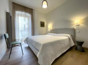 巴多利诺Ancora Suites的卧室配有床、椅子和窗户。