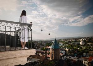 第比利斯纳里卡拉城堡酒店的站在一个俯瞰城市的阳台上的女人