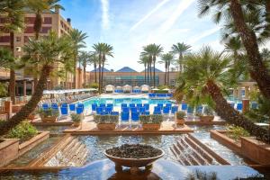 印第安维尔斯Renaissance Esmeralda Resort & Spa, Indian Wells的棕榈树和蓝色椅子的度假村的游泳池