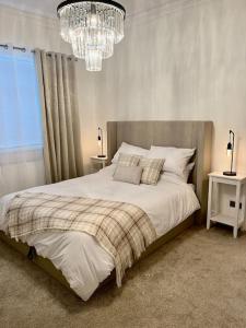 锡厄姆Coastal Apartments No 1的一间卧室配有一张大床和一个吊灯。