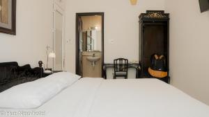 顺化顺化尼诺酒店的卧室配有一张白色大床和吉他