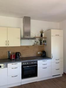 博登斯多夫Ferienwohnung KaRo的厨房配有白色橱柜和黑色用具