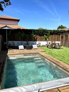 比亚里茨Logement avec piscine privée chauffée的庭院内的游泳池,配有桌椅