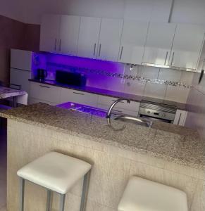 卡什塔涅拉德佩拉Sweet Home - Praia das Rocas的厨房配有2张凳子,位于带紫色照明的柜台