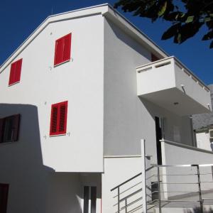 普罗马尼亚Vila Anda的白色的建筑,上面有红色的百叶窗