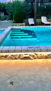 阿彻奇洛斯Aithonas Villa的蓝色游泳池,带两把椅子