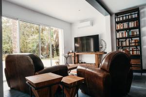 拉特斯特德布赫LA MAISON CACHEE-BA的客厅配有两把椅子、一张桌子和一台电视