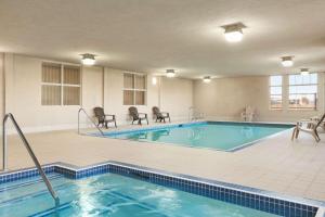 勒杜克温德姆埃德蒙特机场戴斯酒店的游泳池位于酒店客房内,配有椅子和桌子