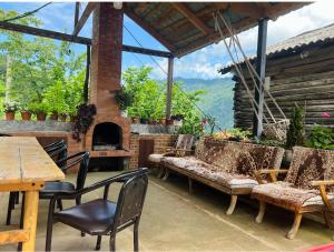 Khelvach'auriAgro Guest House Tsiskari in Machakhela的庭院配有桌椅和壁炉。