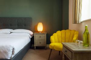 桑德斯富特The Imperial Dragon Hotel的一间卧室配有一张床和一张黄色椅子