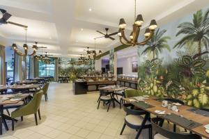 利文斯顿利文斯通普罗蒂亚酒店的餐厅设有桌椅,墙上种植了棕榈树。