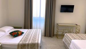 那不勒斯Residenza d’epoca Chiostro San Francesco的酒店客房设有两张床和电视。