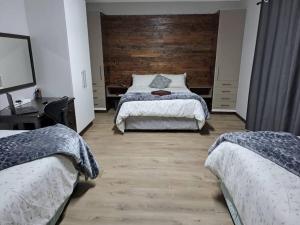 布隆方丹Mossie Nes - Self Catering的一间卧室设有两张床和木墙
