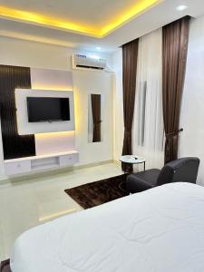 拉各斯Primal Msquare Apartment Ikoyi的配有一张床和一台平面电视的酒店客房