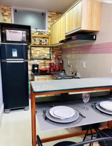 贝伦Studio Bangalô Belém Hospedagem的厨房配有黑色冰箱和盘子