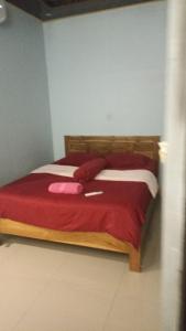 纳闽巴霍De Credo的一间卧室配有一张带红色毯子的木床