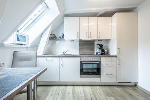 弗伦斯堡fewo1846 - Im Sonnenhof - komfortable 2-Zimmer-Wohnung im Stadtzentrum的厨房配有白色橱柜和桌子