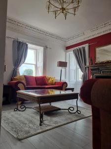 AuchtermuchtyCameron House - spacious B listed building, near Falkland, Central East Scotland的客厅配有红色沙发和茶几