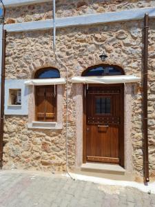 希俄斯Village home的一座石头建筑,设有木门和两扇窗户