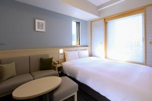 东京Dormy Inn Premium Ginza的酒店客房配有床、桌子和沙发。