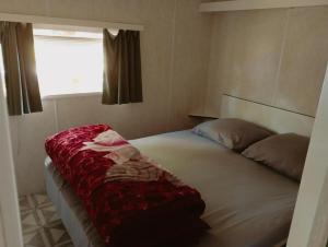 Faux-la-MontagneMOBIL HOME的一间卧室配有一张床铺,床上铺有红色毯子
