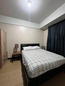 马尼拉Spacious 1 bedroom unit in Araneta Center Cubao的一间卧室配有一张蓝色窗帘的床