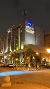 利雅德Continent Al Waha Hotel Riyad的一座大建筑,晚上有标志