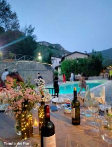FerentilloLa Tenuta dei Fiori的游泳池旁的桌子,上面摆放着葡萄酒瓶和鲜花