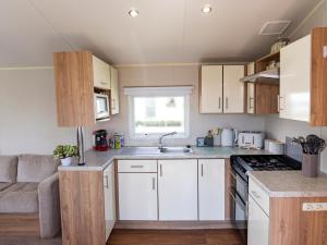 斯凯格内斯Caravan Skegness 8 Berth的小厨房配有白色橱柜和沙发