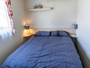 斯凯格内斯Caravan Skegness 8 Berth的一间卧室配有一张带蓝色床单的床和两盏灯。