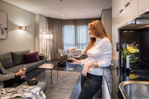 马德里萨巴蒂尼花园公寓酒店的站在一间房间里拿着一杯葡萄酒的女人
