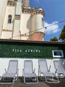 卢索Vila Aurora的一组椅子,坐在一座带灯塔的建筑外