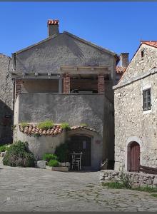 卢本尼彻Lubenice-Rodinis Room and Apartment的石头房子前面有一张桌子和一把椅子