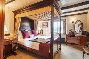 BolventorThe Jamaica Inn, Bodmin, Cornwall的一间卧室配有一张天蓬床、一张桌子和一面镜子